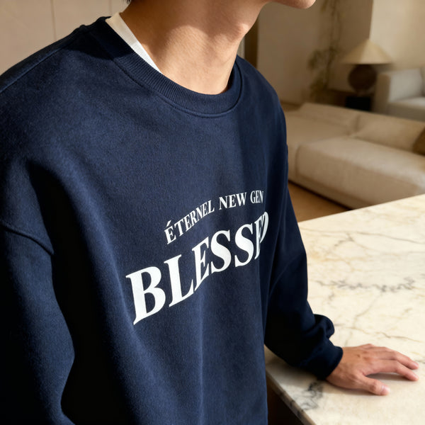Person wearing a navy blue sweatshirt with 'Blessed' text in a modern indoor setting